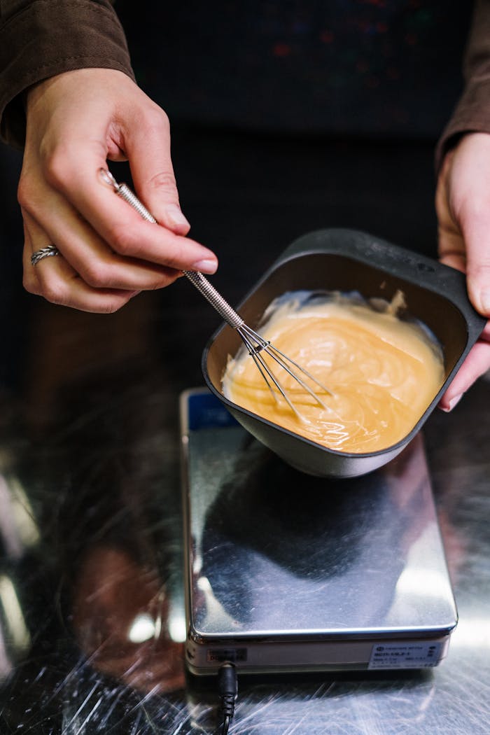 Close-up of hair dye being mixed in a bowl by a stylist, showcasing the process.