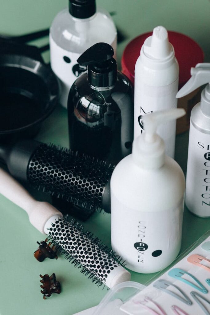 Close-up of hairstyling tools and cosmetic bottles on a green background for salon use.